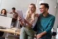 Two young businesspeople using a digital tablet while standing in a boardroom.