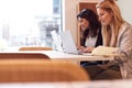 Two Young Businesswomen In Meeting Around Table In Modern Open Plan Workspace Royalty Free Stock Photo