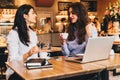 Two young businesswomen sitting in cafe at table and using laptop, working, blogging. Students studying. Royalty Free Stock Photo