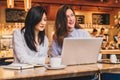 Two young businesswomen sitting in cafe at table and using laptop, working, blogging. Girls are looking at monitor Royalty Free Stock Photo