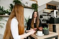 Two young businesswomen are sitting in a cozy cafe, discussing projects and drinking coffee. Two girlfriends office workers in Royalty Free Stock Photo