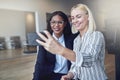 Two young businesswomen smiling while taking selfies in an offic Royalty Free Stock Photo