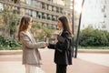 Two young caucasian businesswomen shaking their hands while standing outside modern office. Royalty Free Stock Photo