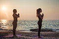 Two young caucasian females practicing yoga on beach Royalty Free Stock Photo