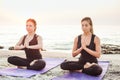 Two young caucasian females practicing yoga on beach Royalty Free Stock Photo