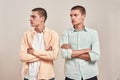 Two young caucasian men, twin brothers looking aside while posing together isolated over beige background Royalty Free Stock Photo