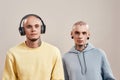 Two young caucasian twin brothers in casual wear with tattoos and piercings listening music in headphones and wireless Royalty Free Stock Photo