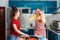 Two young Caucasian women cook pizza in the kitchen and have fun together. Indoors. Concept of joint home cooking for Royalty Free Stock Photo
