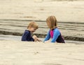 Two young children, a boy and a girl, playing in the sand and water at the beach Royalty Free Stock Photo