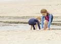 Two young children, a boy and a girl, playing in the sand and water at the beach Royalty Free Stock Photo