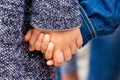 Two young children are holding hands. Girl holds brother by hand_