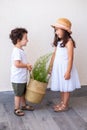 Two young children playing together holding a plant in a trendy straw basket. Royalty Free Stock Photo