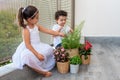 Two Young Children Playing Together, Kids Taking Care Of Plants On Balcony.