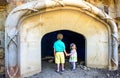 Two young children regard a cave opening at a public garden