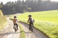 Two young children ride bicycles in park