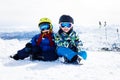 Two young children, siblings brothers, skiing in Austrian mountains on a sunny day