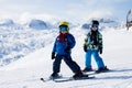 Two young children, siblings brothers, skiing in Austrian mountains on a sunny day
