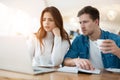 Two young colleagues brunette woman and handsome man working in laptop during lunch break at cafe, looking serious, teamwork and