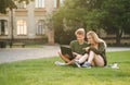 Two young college students watching funny video on the laptop, preparing for the exam with computer sitting on the lawn. Couple of Royalty Free Stock Photo