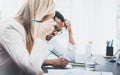 Two young coworkers working together on modern business project.Man wearing glasses and making notes at the