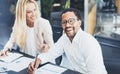 Two young coworkers working together in a modern office.Man wearing glasses, looking at the camera and smiling.Woman discussing wi Royalty Free Stock Photo