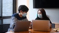 Two young creative designer in protective masks works together in office. Royalty Free Stock Photo