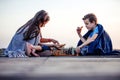 Two young cute little friends, boy and girl having fun while playing chess sitting covered with blanket by the lake Royalty Free Stock Photo