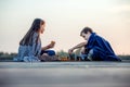 Two young cute little friends, boy and girl having fun while playing chess sitting by the lake in the evening Royalty Free Stock Photo