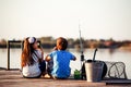 Two young cute little friends, boy and girl talking, eating sandwiches and fishing on a lake in a sunny summer day Royalty Free Stock Photo