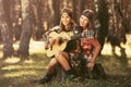 Two young fashion girls with guitar in summer forest Royalty Free Stock Photo