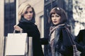 Two young fashion women with shopping bags next to mall door Royalty Free Stock Photo