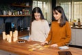 Two young femaies laying out deck of tarot cards in a kitchen. Candles and mobile devices present Royalty Free Stock Photo