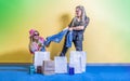 Two pretty girls are fighting over new clothes. Denim pants ripping open. There are shopping bags nearby. Royalty Free Stock Photo