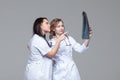 Two young female doctors studying the x-ray picture of lungs on grey background Royalty Free Stock Photo