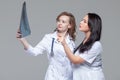 Two young female doctors studying the x-ray picture of lungs on grey background Royalty Free Stock Photo