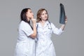 Two young female doctors studying the x-ray picture of lungs on grey background Royalty Free Stock Photo