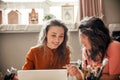 Two young female entrepreneurs sit with laptop in their workshop