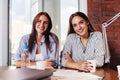 Two young female entrepreneurs sitting at work desk during the business meeting in modern conference room Royalty Free Stock Photo