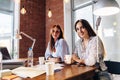 Two young female entrepreneurs sitting at work desk during the business meeting in modern conference room Royalty Free Stock Photo