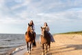 Two young female friends riding horses together on a sunny beach Royalty Free Stock Photo