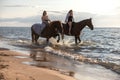 Two young female friends riding horses together on a sunny beach Royalty Free Stock Photo