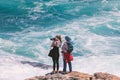 Two young female tourists photographing ocean scene from the edge of the rocks