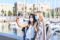 Two young female tourists taking a self picture in leisure port during Covid19 pandemic