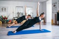 Two young females doing side plank with raised arm static strengthening core muscles in Vasisthasana position exercise on floor Royalty Free Stock Photo