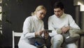 Two young fencers man and woman watching fencing tutorial on smartphone and sharing experience after training indoors