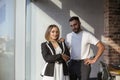 Two young focused coworkers, woman and man, looking at camera standing in office