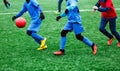 Two young Footballers in red and blue sportswear running,dribble and competing for ball. Junior football match competition. Winter
