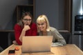 Two young freelance business women teamwork working at home on laptop as product strategy expert. Female expatriate remote work on