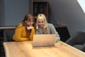 Two young freelance business women teamwork working at home on laptop as product strategy expert. Female expatriate remote work on