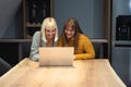 Two young freelance business women teamwork working at home on laptop as product strategy expert. Female expatriate remote work on